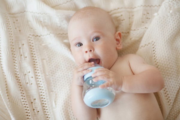 Младенец пьет воду из бутылочки