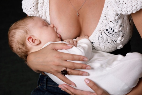 Женщина кормит малыша грудью