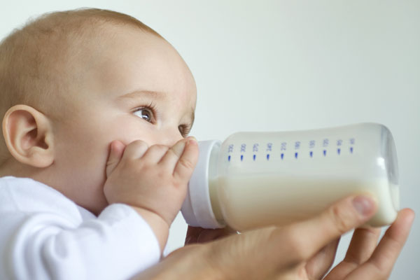 Ребенок пьет молоко из бутылочки